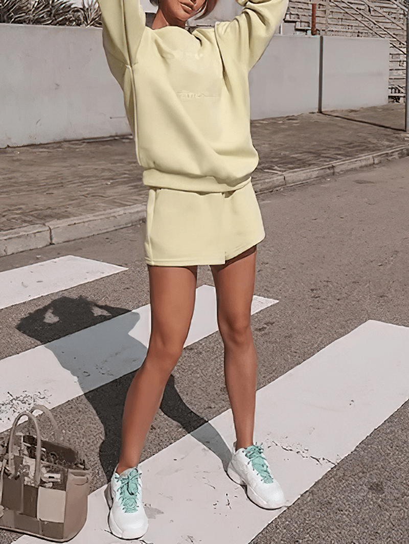 Woman in trendy yellow sweatshirt and shorts set stands confidently outdoors, showcasing letter embroidery style. SF1588 fashion.